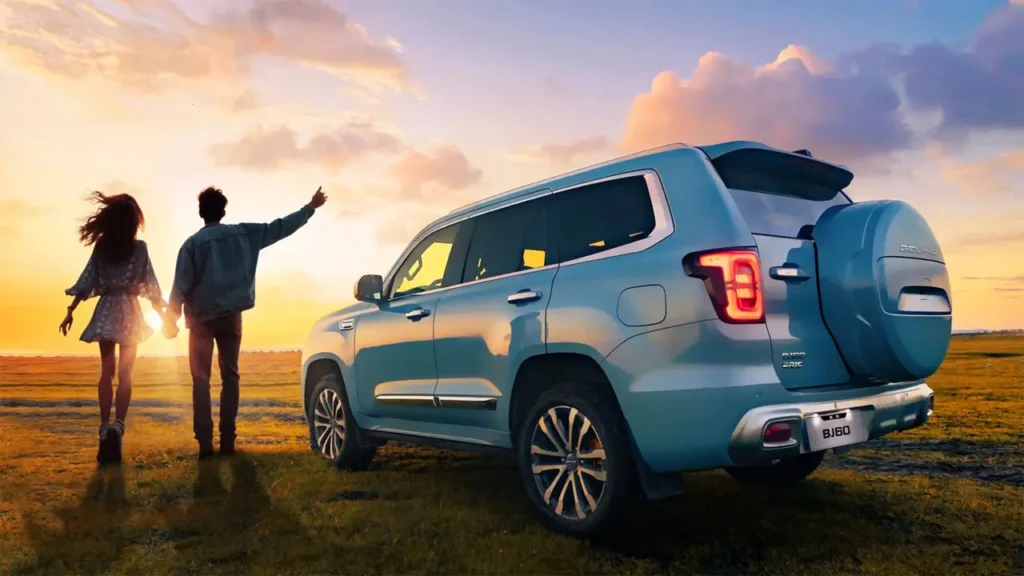 Couple next to BAIC BJ60 at sunset — adventure-themed atmosphere.