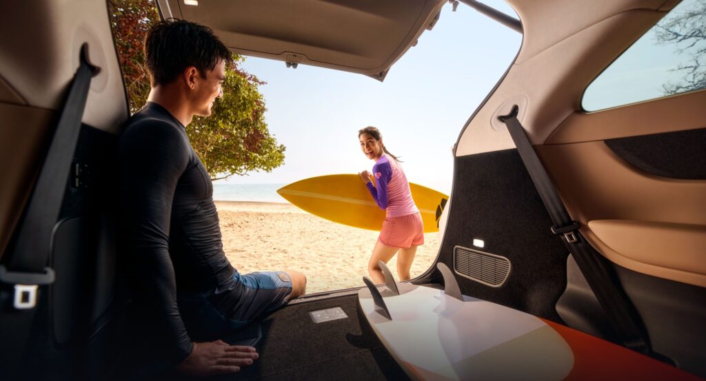 Inside Xpeng X9 trunk with surfers on beach